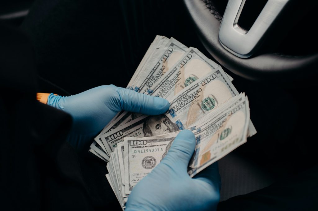Businessman wears medical protective gloves, counts dirty money, holds dollar banknotes